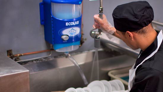 Dishwasher at restaurant cleaning dishes with Ecolab branded cleaner. 