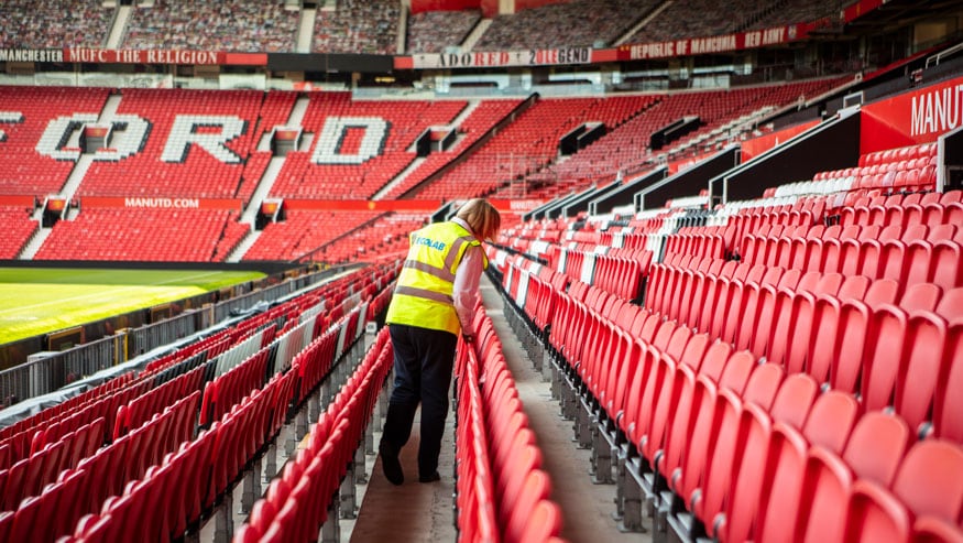 Ecolab associate wearing a company vest inspecting the stands at Manchester United's Old Stafford Stadium.