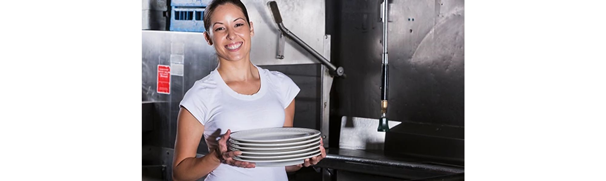 Person Holding Stack of Plates in Commercial Kitchen